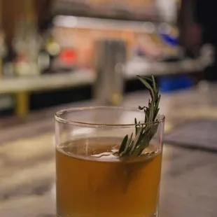 a drink with a sprig of rosemary