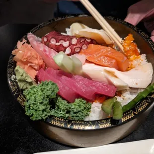 a bowl of sushi with chopsticks
