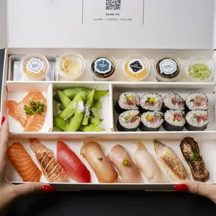 a woman holding a box of sushi