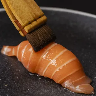 a piece of sushi being brushed with a brush