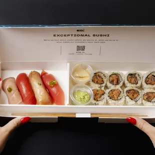 a woman holding a box of sushi