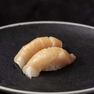 two pieces of sushi on a black plate