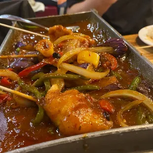 Skewered fish with vegetables on a hot plate