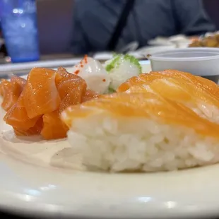 Translucent thin sliced Salmon sushi with poke salmon and ika in the background.