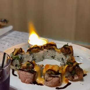 a plate of sushi with a lit candle in the background