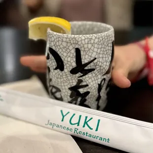 a person holding a cup with a slice of lemon in it