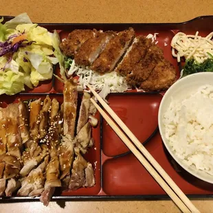 a bento tray with rice, meat, and vegetables