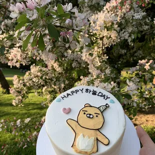 a hand holding a birthday cake