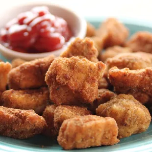 a plate of fried chicken nuggies and a bowl of ketchup