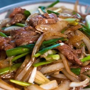 a plate of stir fried beef and onions