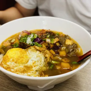 a bowl of soup with an egg in it