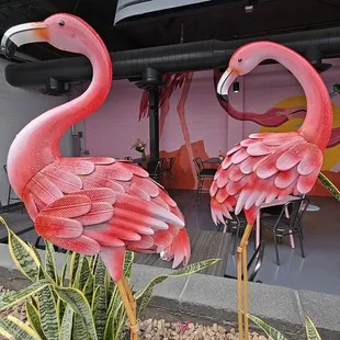 two pink flamingos in front of a restaurant