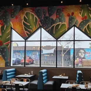 a view of a restaurant with a colorful mural on the wall