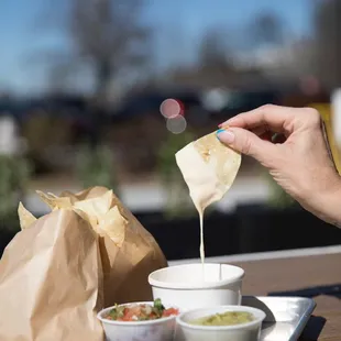 a hand dipping a tortilla