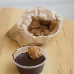 a small bowl of chocolate sauce and a bag of cookies