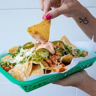 a person holding a tray of nachos