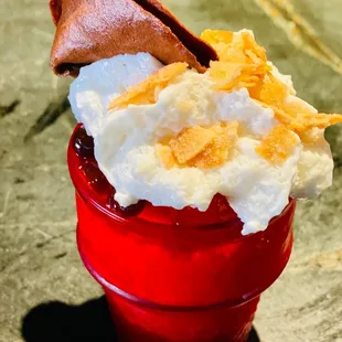 a red cup filled with whipped cream and fruit