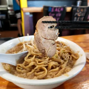 a bowl of noodles with meat and chopsticks