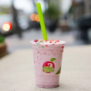 a pink smoothie with a green straw