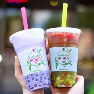 a hand holding two boba cups