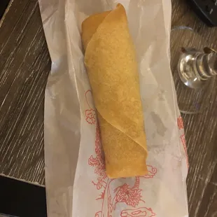 a sandwich wrapped in paper on a table