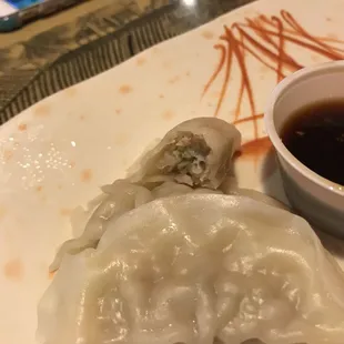 a plate of dumplings and a bowl of sauce