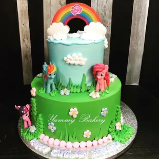 a cake decorated with a rainbow and ponies