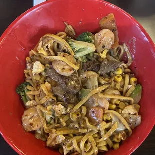a red bowl of stir fry and noodles