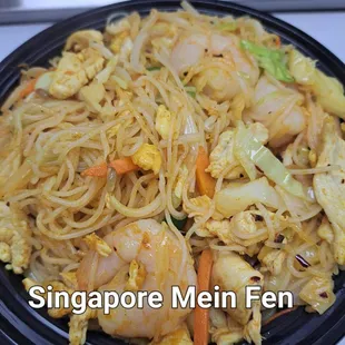 a plate of noodles with shrimp and vegetables