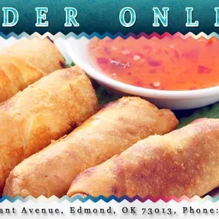 a plate of fried spring rolls with dipping sauce