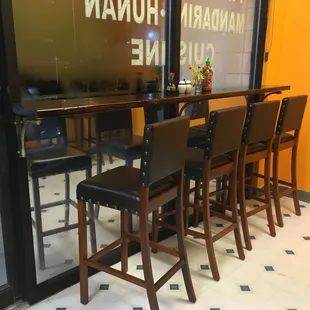 a row of bar stools in front of a window