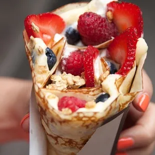 a person holding a fruit filled crepe