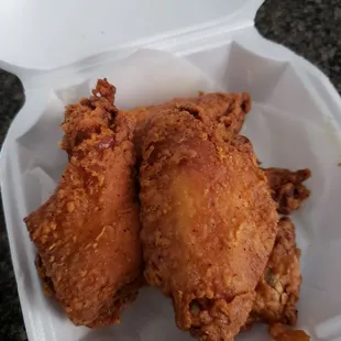 two pieces of fried chicken in a styrofoam container