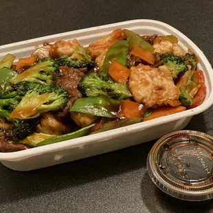 a container of stir fry with broccoli and carrots