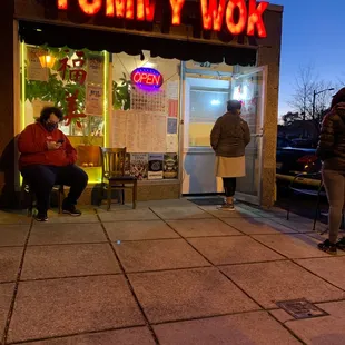 two people sitting on a bench in front of a yummy wok