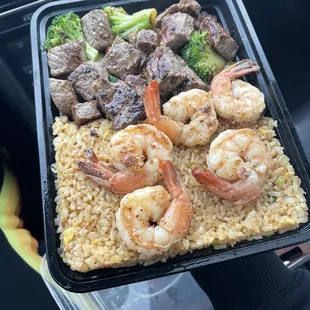 Shrimp and steak over garlic fried rice with vegetables