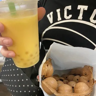 a person holding a drink and a basket of nuts