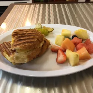 Breakfast croissant sandwich with bacon egg and cheese. Fruit salad on the side. Delicious!