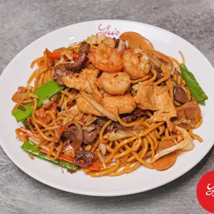 a plate of noodles with shrimp and vegetables