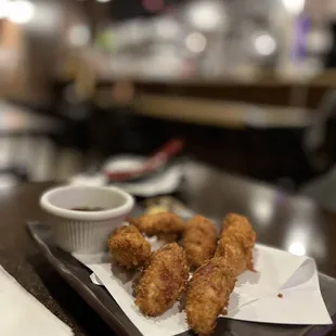 a tray of fried chicken sticks and dipping sauce