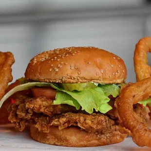 a burger with onion rings and lettuce