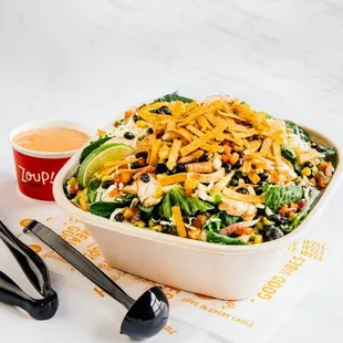 a salad in a bowl with a side of dressing