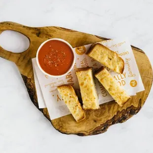 a bowl of tomato soup and breadsticks