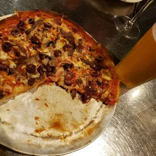 a half eaten pizza and a glass of beer