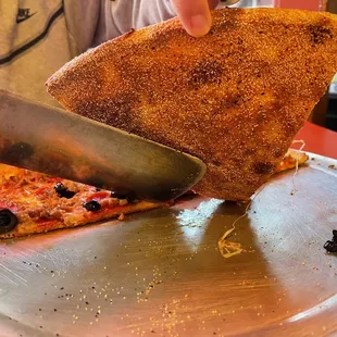 a person cutting a slice of pizza