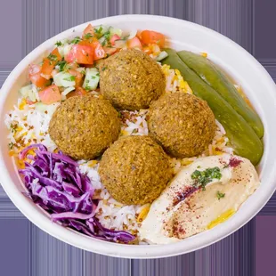 Falafels on rice and topped with salad, hummus, red cabbage, pickles, &amp; tahini sauce