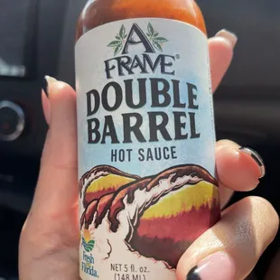 a hand holding a bottle of hot sauce