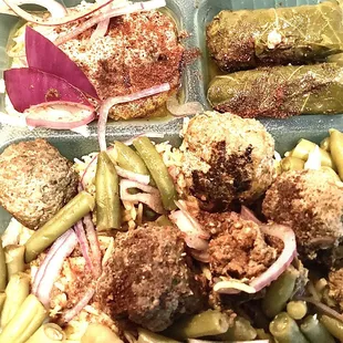 Combination rice plate with meatballs, green beans, cooked with garlic and tomato, stuffed grape leaves, and hummus.