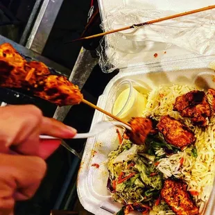 chicken skewers and noodles in a styrofoam container