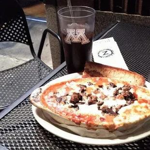 Dinner al fresco:  lasagna, with mushrooms added, bread, and a soft drink in a glass with the emblem of the area stalwart that is UMinn.